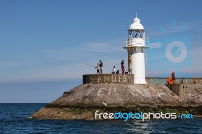 Brixham, Devon/uk - July 28 : People Fishing Near The Lighthouse… Stock Photo