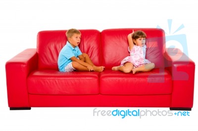 Brother And Sister On Red Sofa Stock Photo