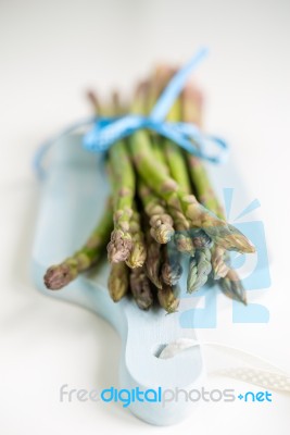 Bunch Of Fresh Asparagus On A Blue Wooden Cutting Board Stock Photo