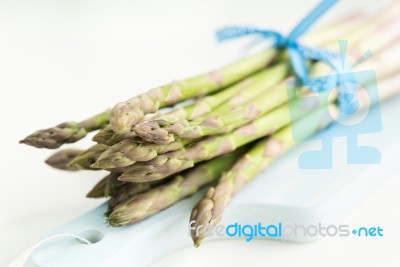 Bunch Of Fresh Asparagus On A Blue Wooden Cutting Board Stock Photo