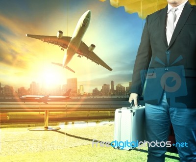 Business Man And Breifcase Standing In Airport Terminal Building And Passenger Plane Arrival On Runway Stock Photo