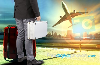 Business Man And Breifcase ,traveling Luggage Standing In Airport Terminal Building And Passenger Plane Flying Over Sky Stock Photo