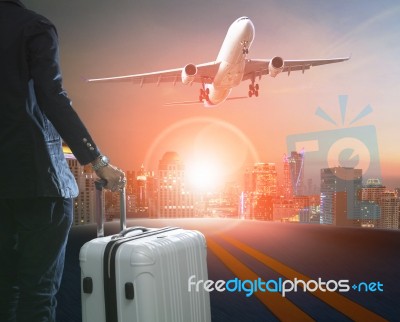 Business Man And Traveling Luggage Standing Against Skyline And Passenger Plane Taking Over Airport Runway Stock Photo