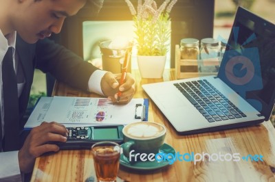 Business Man Sitting On A Calculator To Figure Out In A Coffee S… Stock Photo