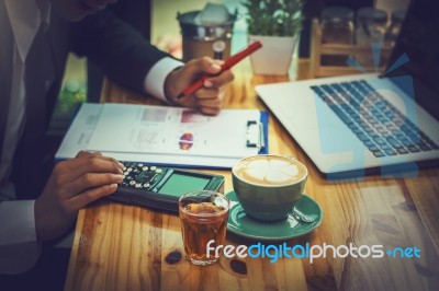 Business Man Sitting On A Calculator To Figure Out In A Coffee S… Stock Photo