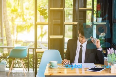 Business Man Sitting On A Calculator To Figure Out In A Coffee S… Stock Photo