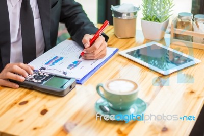 Business Man Sitting On A Calculator To Figure Out In A Coffee S… Stock Photo