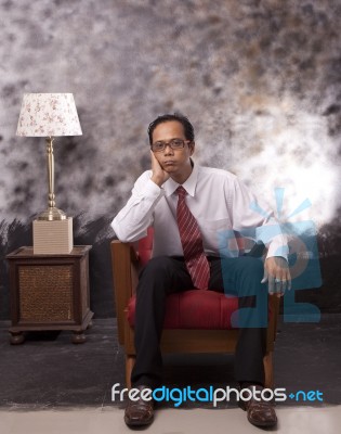 Business Man Sitting On Wood Sofa With Serious Face Stock Photo