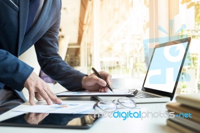 Business Man Working At Office With Laptop, Tablet And Graph Dat… Stock Photo