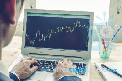 Businessman Analyze Stock Graph Or Forex Graph By Laptop On Blue Vintage Style Stock Photo