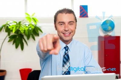 Businessman At Work Desk Pointing At You Stock Photo