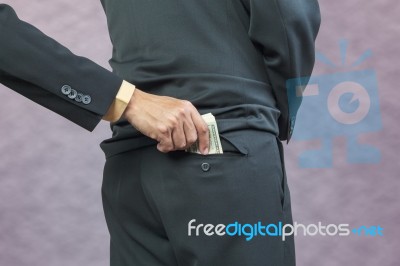 Businessman Hand Put Money To Back Pocket Stock Photo