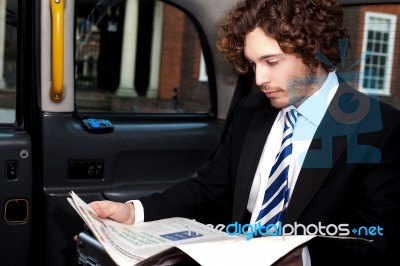 Businessman Reading Magazine Inside Taxi Stock Photo