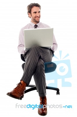 Businessman Sitting On The Chair With Laptop Stock Photo