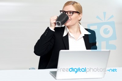 Businesswoman Enjoying Coffee At Work Desk Stock Photo