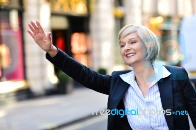 Businesswoman Raising Her Arm To Call A Taxi Stock Photo