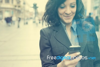 Businesswoman With Smartphone Walking On Street Stock Photo