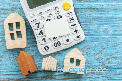 Calculator And Wood Houses On Wood Background Stock Photo