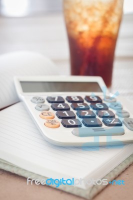 Calculator On Blank Notebook With A Glass Of Cola Stock Photo