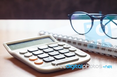 Calculator With Eyeglasses On Wooden Table Stock Photo