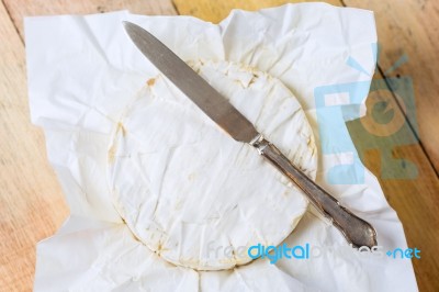 Camembert Cheese Wrapped In Paper With Vintage Knife On Wooden T… Stock Photo