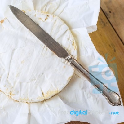 Camembert Cheese Wrapped In Paper With Vintage Knife On Wooden T… Stock Photo