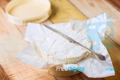 Camembert Cheese Wrapped In Paper With Vintage Knife On Wooden T… Stock Photo