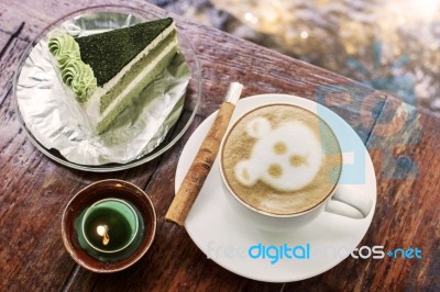 Cappuccino Coffee With Cinnamon Stick And Green Tea Cake On Table With Candle Stock Photo