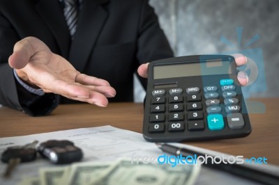 Car Salesman Holding A Key And Calculating A Price At The Dealer… Stock Photo