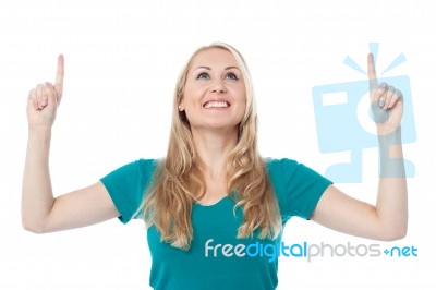 Casual Woman Looking And Pointing Upwards Stock Photo