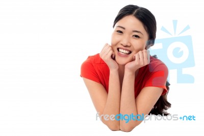 Casual Young Chinese Girl Lying On Studio Floor Stock Photo