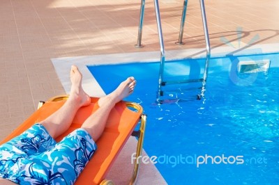 Caucasian Teenage Boy Lying On Stretcher Near Swimming Pool Stock Photo