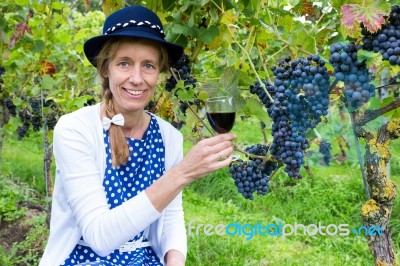 Caucasian Woman Toasting With Glass Of Wine Near Bunches Of Blue… Stock Photo