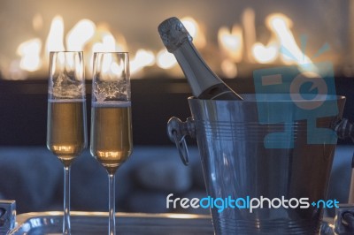 Champagne Flutes And Bottle By The Fire Stock Photo