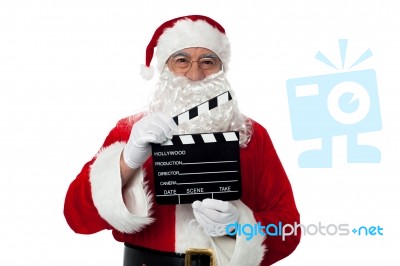 Cheerful Aged Santa Posing With A Clapperboard Stock Photo