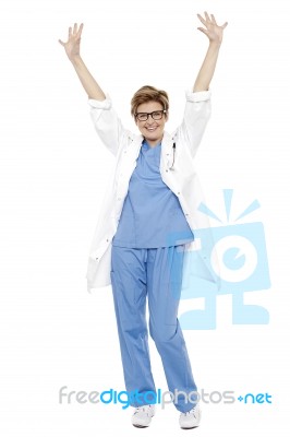 Cheerful Doctor Raising Her Hands Up In Celebration Stock Photo