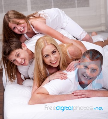 Cheerful Family Having Fun Together Lying On A Bed Stock Photo