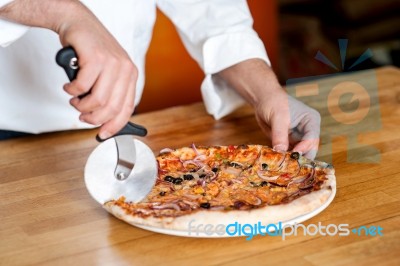 Chef Cutting Pizza With Cutter Stock Photo