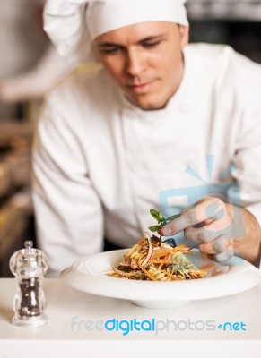 Chef Decorating Pasta Salad With Herbal Leaves Stock Photo