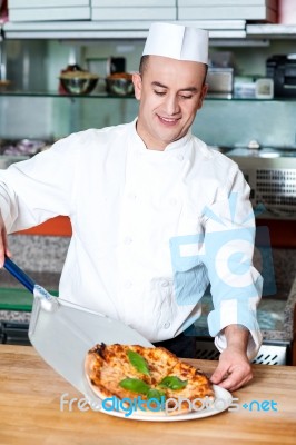 Chef Placing Pizza, Ready To Be Served Stock Photo