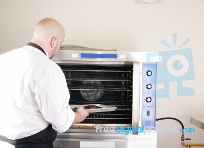 Chef Putting A Tray Of A Juicy Steak In A Professional Oven Stock Photo