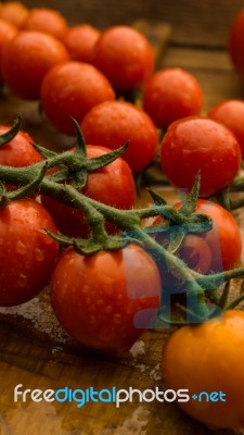 Cherry Tomatoes On Display On Wooden Chopping Board And Wooden Table Stock Photo