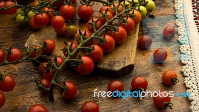 Cherry Tomatoes On Display On Wooden Chopping Board And Wooden Table Stock Photo