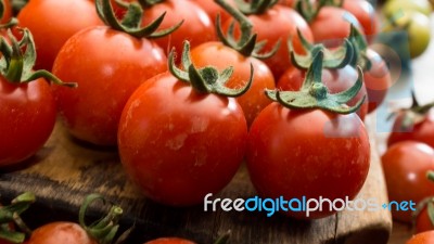 Cherry Tomatoes On Display On Wooden Chopping Board And Wooden Table Stock Photo