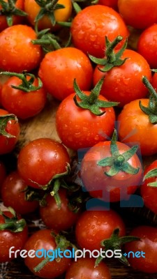 Cherry Tomatoes On Display On Wooden Chopping Board And Wooden Table Stock Photo