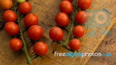 Cherry Tomatoes On Display On Wooden Chopping Board And Wooden Table Stock Photo