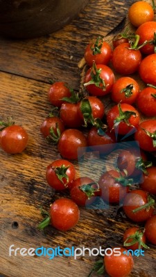 Cherry Tomatoes On Display On Wooden Chopping Board And Wooden Table Stock Photo