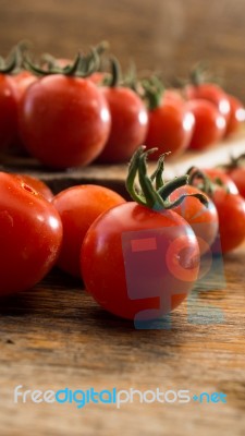 Cherry Tomatoes On Display On Wooden Chopping Board And Wooden Table Stock Photo