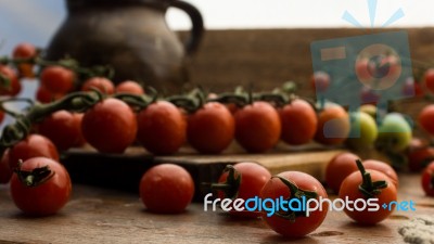 Cherry Tomatoes On Display On Wooden Chopping Board And Wooden Table Stock Photo