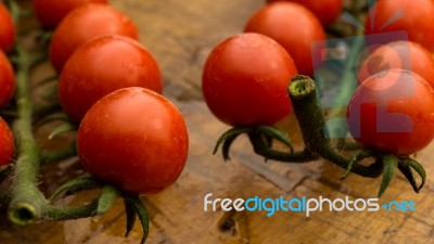 Cherry Tomatoes On Display On Wooden Chopping Board And Wooden Table Stock Photo